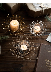 Detailed view of festive crystal beads wreath with glass candle holder on wooden desk