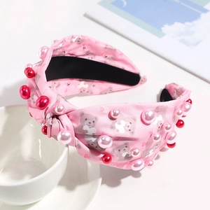 Detail of pink knotted headband featuring cute teddy bear prints and faux pearls