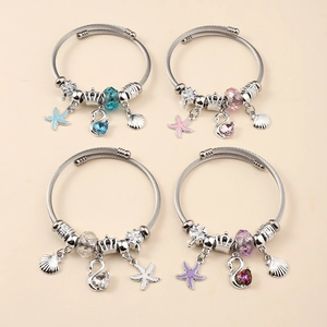 Detail of four adjustable stainless steel wire bracelets with crystal swan and sea star charms