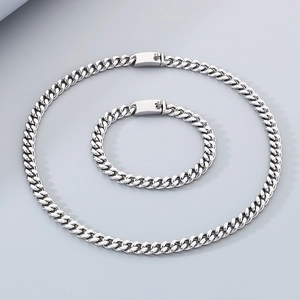 Macro shot of silver stainless steel cuban link necklace and bracelet set on grey surface