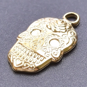 Macro shot of 18k gold plated sugar skull pendant with intricate floral engravings