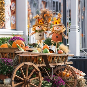 Détail de deux épouvantails d'automne placés dans une charrette en bois rustique