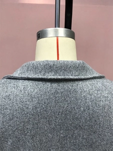 Gros plan du col arrière d'un manteau en laine grise montrant coutures et texture