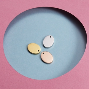 Detailed view of oval stainless steel pendants in gold, silver, and rose gold finishes