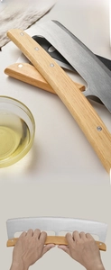 Macro detail of stainless steel mezzaluna pizza cutter with ergonomic wooden handle
