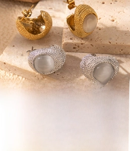 Detailed view of gold and silver C-shaped titanium steel earrings with cubic zirconia inlay