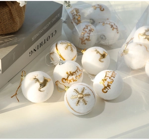 Close-up of white flocked Christmas ball with gold reindeer and snowflake patterns