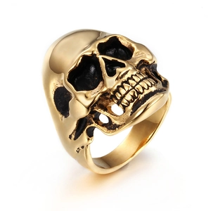 Polished gold stainless steel skull ring with gothic black detailing on white background