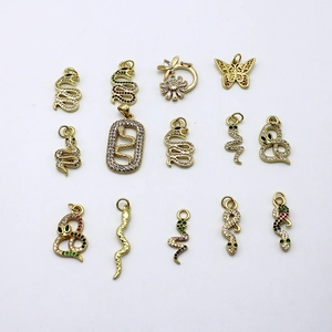 Macro shot of 18K gold plated snake, butterfly and flower pendants with cubic zirconia