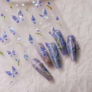 Iridescent purple butterfly and blue tulip nail art stickers shown on long manicured nails