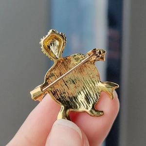Detail view of the golden metal turtle brooch back with secure safety pin closure
