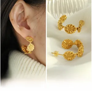 Detailed view of matte gold sunflower hoop earrings shown on model and white fabric