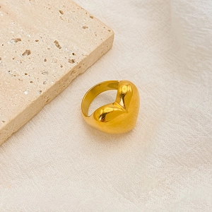 Detaillierte Nahaufnahme eines polierten goldenen Herzrings auf einem Marmorhintergrund