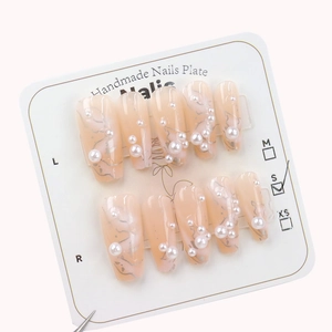 Pink coffin press-on nails with silver glitter lines and pearl accents on a size card