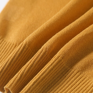 Detail of ginger yellow knit fabric showing fine ribbed edges and soft texture