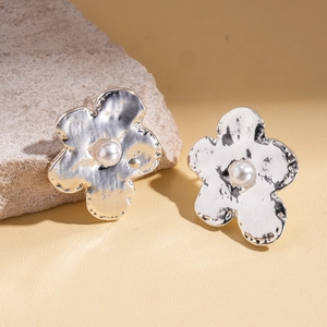 Elegant silver metallic flower stud earrings with pearl centers on natural stone base