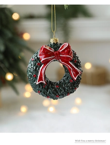 Close-up of green Christmas wreath ornament with red bow and gold string on festive bokeh