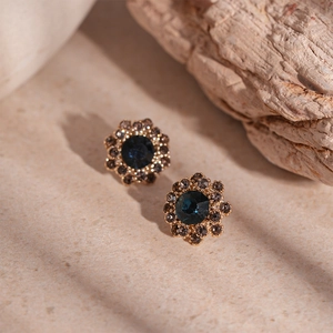 Close-up of vintage gold flower earrings with deep blue gems and sparkling rhinestones