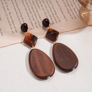 Detail view of retro wood and amber resin drop earrings on a vintage book backdrop
