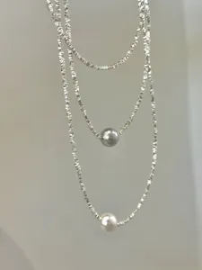 Macro detail of layered S925 silver chain featuring grey and white pearls