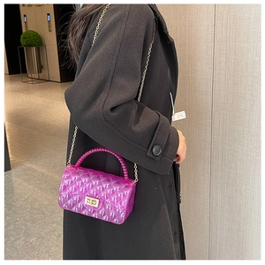 Detail of purple jelly crossbody bag with quilted texture, pearl handle and gold chain