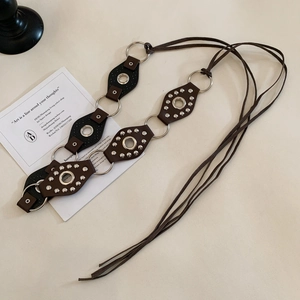 Detail of vintage leather belt with geometric cutouts, silver rivets and metal rings