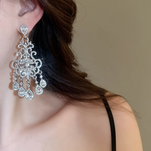 Detail of silver tassel earrings with floral pattern and sparkling teardrop crystals