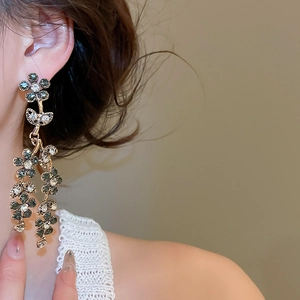 Detail of vintage gold flower tassel earrings with green and white rhinestones