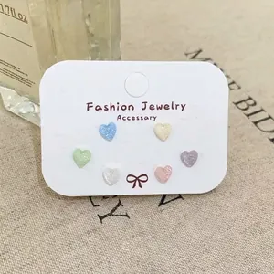 Close-up of six pairs of heart-shaped earrings in macaron colors with glitter finish