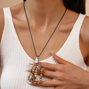 Detail view of ethnic beaded necklace with brown fringe and silver clasp on model