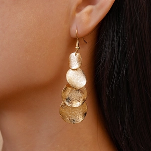 Gros plan de boucles d'oreilles dorées mates avec quatre disques circulaires étagés