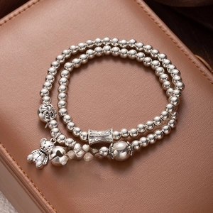 Close-up of beaded tassel bracelet with bear and heart charms on brown leather