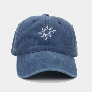 Detail of sun embroidery on navy blue washed cotton baseball cap with white stitching