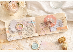 Close-up of vintage scrapbook kit featuring embossed lace paper and floral stickers