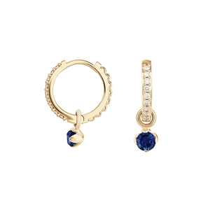 Detail view of gold hoop earrings with pavé stones and a blue round gemstone pendant