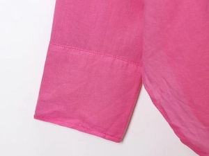 Close-up of pink buttoned shirt cuff with detailed flat stitching and plain weave fabric