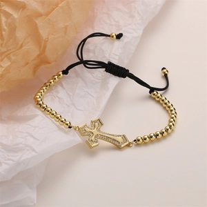 Detail of adjustable woven bracelet with a gold-plated cubic zirconia cross charm