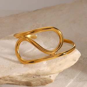 Nahaufnahme der goldenen minimalistischen Manschette mit poliertem Finish auf Stein