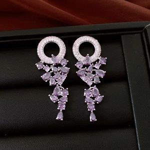 Detailed view of silver hoop earrings featuring purple teardrop crystals and zircons
