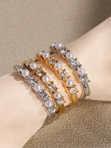 Macro detail of four gold and silver stackable rings with pearls and cubic zirconia