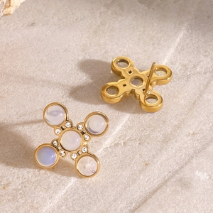 Macro shot of gold cross stud earrings featuring translucent white stones and tiny crystals