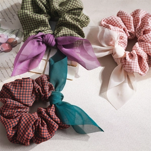 Three checkered fabric scrunchies with elegant chiffon bows in assorted pastel colors