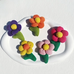 Detail of colorful knitted plaid flowers with green leaves in a white ceramic tray