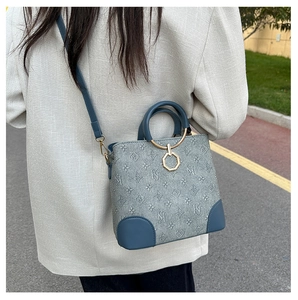 Blue-grey bucket bag with floral monogram print and round top handle on street model
