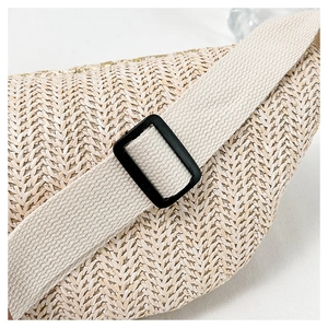 Detail of beige straw fanny pack showing herringbone texture and adjustable strap buckle