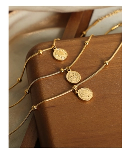 Macro shot of 18k gold plated snake chain bracelet with vintage coin pendant