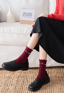 Detail of wine red cotton socks featuring ruffled edges and delicate pearl embellishments