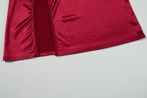 Detailed close-up of burgundy satin dress showing side slit and delicate ruching texture