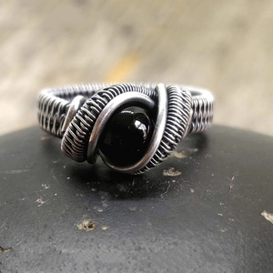 Vintage silver knot ring with oval black onyx gemstone on natural dark stone base