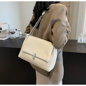 Detail of the chic beige shoulder bag featuring a silver metal buckle and chain strap